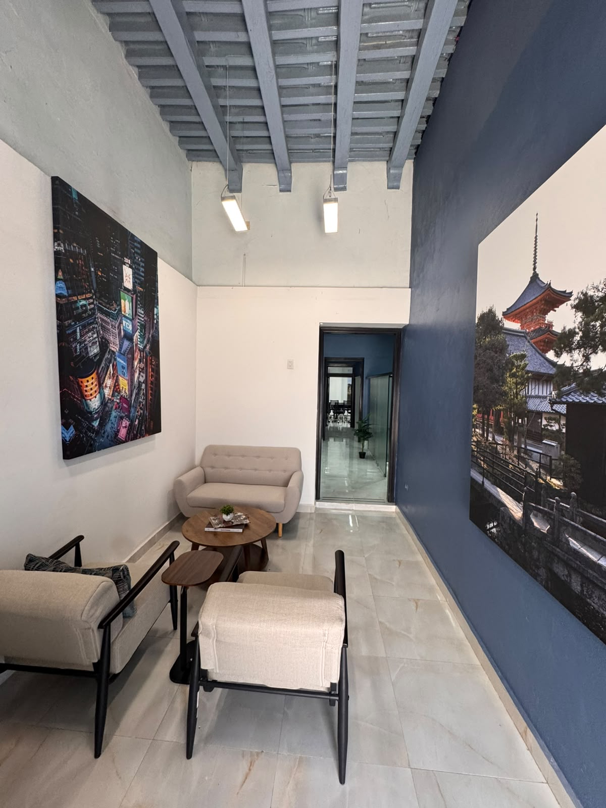 Lounge de NEXO Business Center: muro azul, techo de viguetas y área de estar.